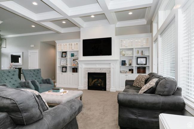 Living room featuring crown molding, a fireplace, light colored carpet, coffered ceiling, and beam ceiling | Image 28