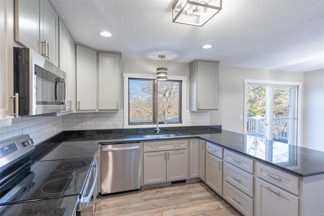 Kitchen with sink, hanging light fixtures, stainless steel appliances, light hardwood / wood-style flooring, and kitchen peninsula | Image 41