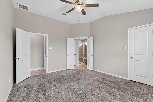 Unfurnished bedroom with vaulted ceiling, light colored carpet, connected bathroom, and a ceiling fan | Image 18