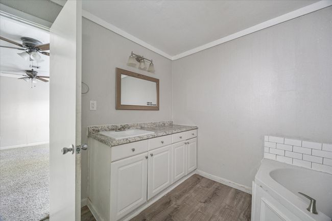 Bathroom with vanity, ceiling fan, a bath, wood finished floors, and crown molding | Image 17