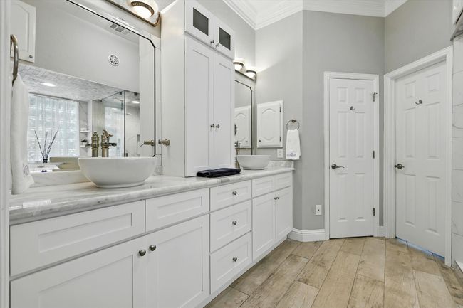 Primary full bathroom with crown molding, double vanity, built in soap dispenser, cermaic tile wood-like floors | Image 16