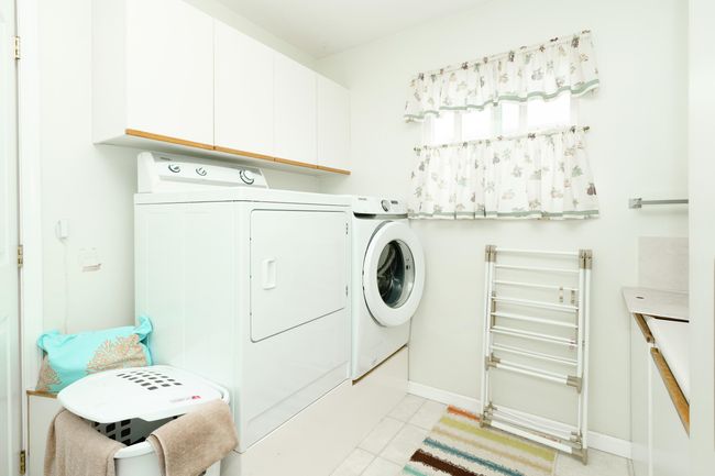 Washroom featuring independent washer and dryer, cabinet space, light tile patterned floors, and baseboards | Image 16