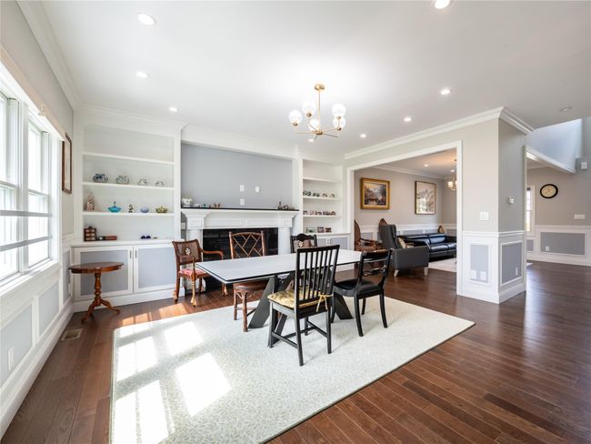 Dining area featuring built in shelves, visible vents, a fireplace, ornamental molding, and dark wood-style floors | Image 4