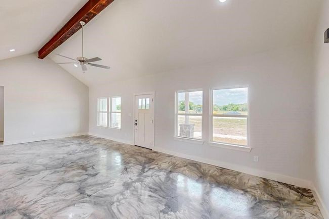 Unfurnished living room featuring lofted ceiling with beams, ceiling fan, baseboards, and concrete floors | Image 6