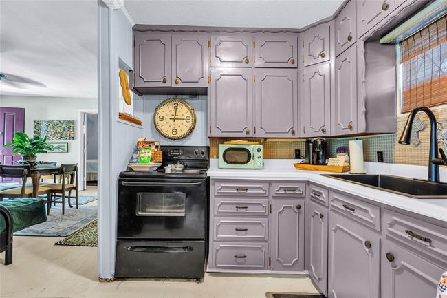 Kitchen with black electric range oven, a sink, light countertops, tasteful backsplash, and gray cabinets | Image 35