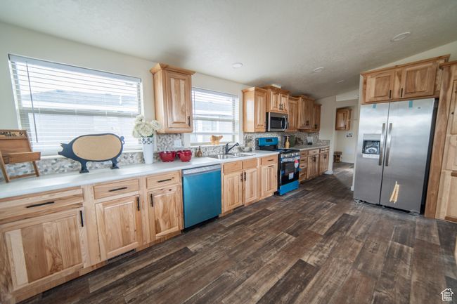 Kitchen featuring a sink, dark wood-style flooring, lofted ceiling, decorative backsplash, and appliances with stainless steel finishes | Image 8