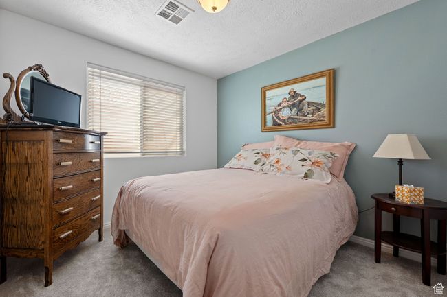 Carpeted bedroom featuring a textured ceiling, visible vents, and baseboards | Image 17