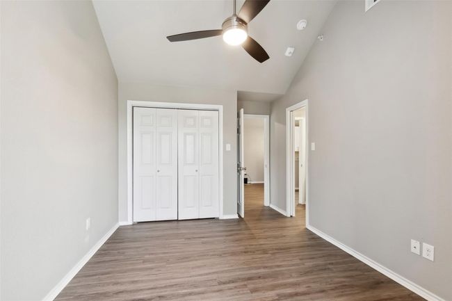 Unfurnished bedroom with wood finished floors, a closet, a ceiling fan, and high vaulted ceiling | Image 12