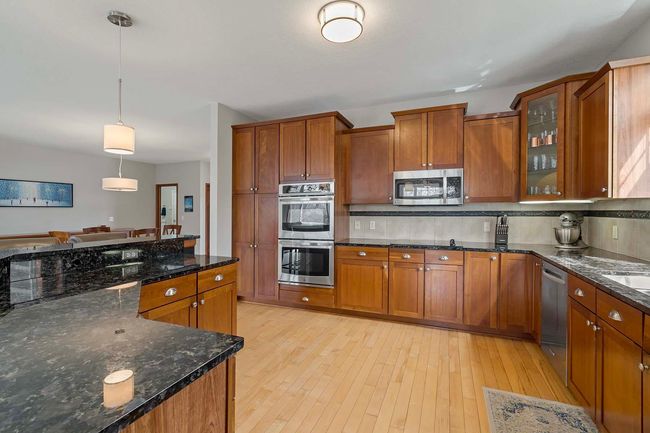The kitchen shines with cherry cabinetry, granite countertops, stainless steel appliances and hardwood floors. | Image 6