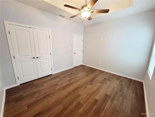 Unfurnished bedroom with a closet, baseboards, a ceiling fan, visible vents, and wood finished floors | Image 13