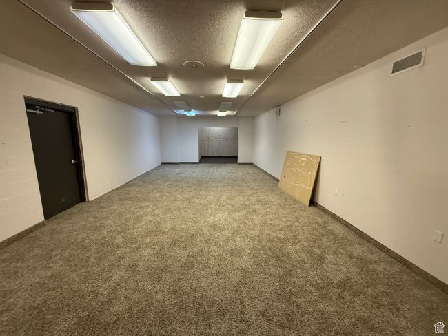 Finished below grade area featuring carpet flooring, a textured ceiling, and visible vents | Image 19