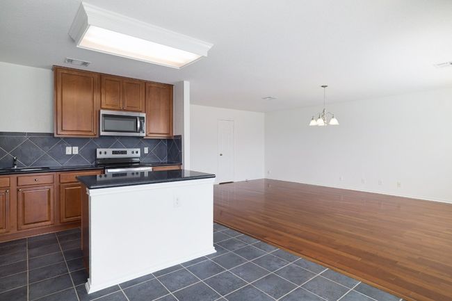 Kitchen with an inviting chandelier, dark tile patterned floors, appliances with stainless steel finishes, dark countertops, and visible vents | Image 14