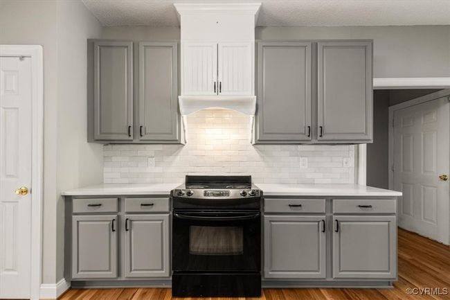 Kitchen featuring gray cabinetry, black range, light countertops, backsplash, and a textured ceiling | Image 20