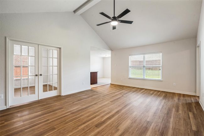 Spare room featuring beamed ceiling, wood finished floors, high vaulted ceiling, a ceiling fan, and french doors | Image 4