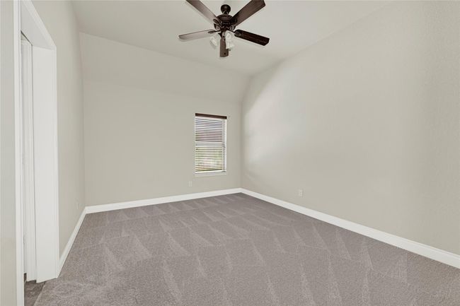 This additional upstairs bedroom offers a peaceful retreat, with a tall window, neutral tones, and a ceiling fan for comfort. | Image 35