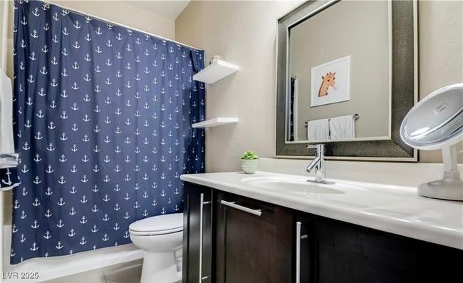 Bathroom featuring a shower with curtain, vanity, and toilet | Image 12
