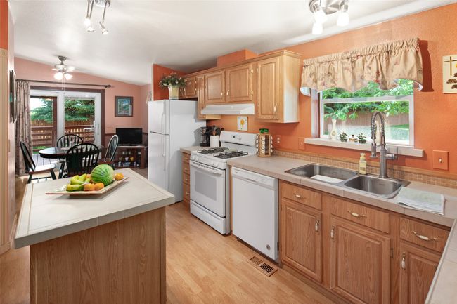 Kitchen featuring white appliances, under cabinet range hood, lofted ceiling, light wood finished floors | Image 15