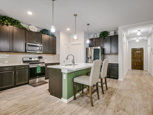 This inviting kitchen is designed for effortless, casual living, whether you're cooking for one, hosting family dinners, or entertaining guests. The spacious island offers plenty of room for meal prep, quick bites, or socializing, while the open layout ensures everyone feels connected. Dark cabinetry and stainless steel appliances provide a modern touch, while the wood-look flooring adds warmth and durability. With stylish pendant lighting and ample storage, this kitchen is as functional as it is welcoming, perfect for creating memories with loved ones or enjoying a quiet evening at home. The Kitchen and Bathroom Cabinets are Soft Close. | Image 4