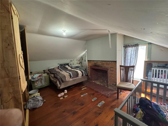 Bedroom featuring lofted ceiling, a brick fireplace, and hardwood / wood-style flooring | Image 23
