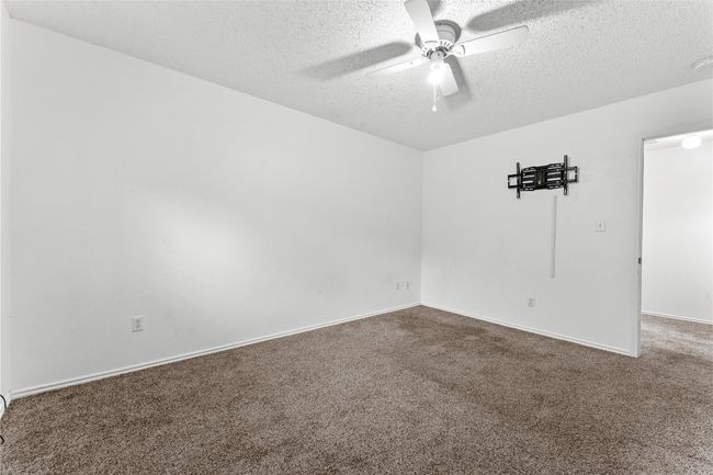 Carpeted empty room featuring a textured ceiling, a ceiling fan, and baseboards | Image 29