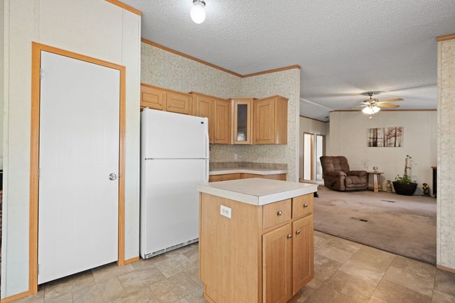 Kitchen with freestanding refrigerator, ornamental molding, a textured ceiling, a ceiling fan, and a center island | Image 12