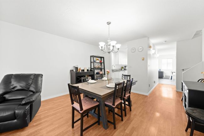 Dining area with light wood finished floors, a notable chandelier, and baseboards | Image 12