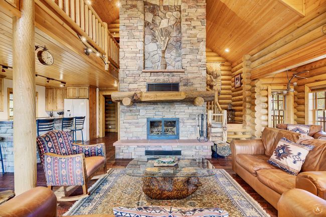 Living room featuring a stone fireplace, wood ceiling, log walls, hardwood / wood-style floors, and high vaulted ceiling | Image 6