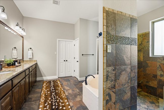 Full bathroom with a bath, double vanity, walk in shower, and stone tile floors | Image 23