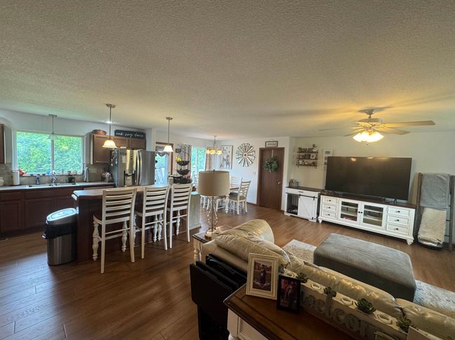 Living area with a textured ceiling, a ceiling fan, and dark wood-style flooring | Image 14