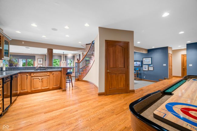recreation room featuring recessed lighting, decorative columns, a sink, baseboards, and light wood-type flooring | Image 64
