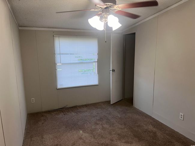 Carpeted spare room with ceiling fan, a textured ceiling, and crown molding | Image 9