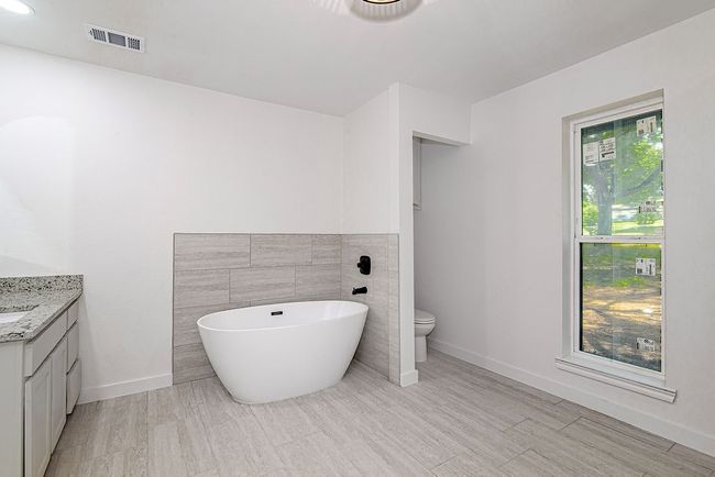 Full bath with vanity, a soaking tub, toilet, and baseboards | Image 23