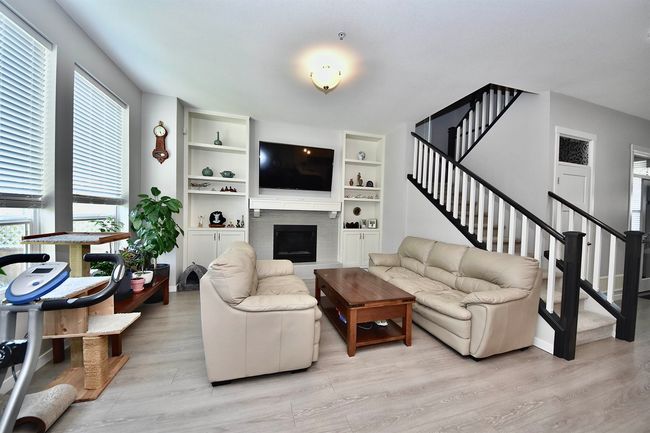 Living room with light wood-style floors, stairs, a fireplace, and built in shelves | Image 10