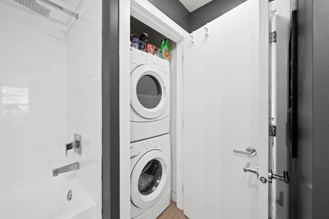 Laundry area featuring stacked washer / dryer, laundry area, and light wood finished floors | Image 20