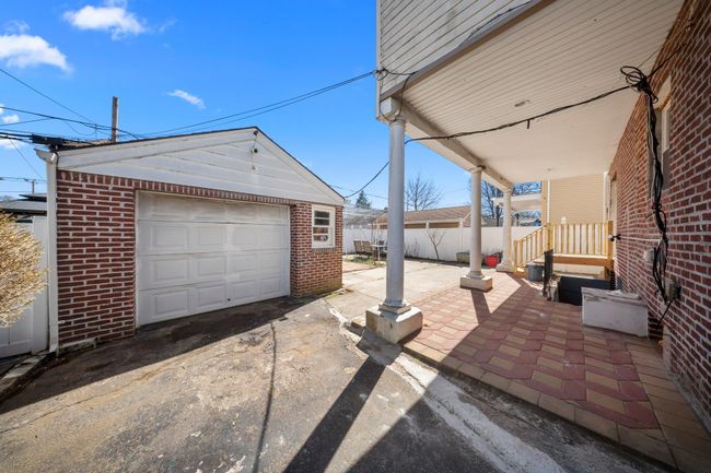 View of patio with an outdoor structure, concrete driveway, fence, and a detached garage | Image 24