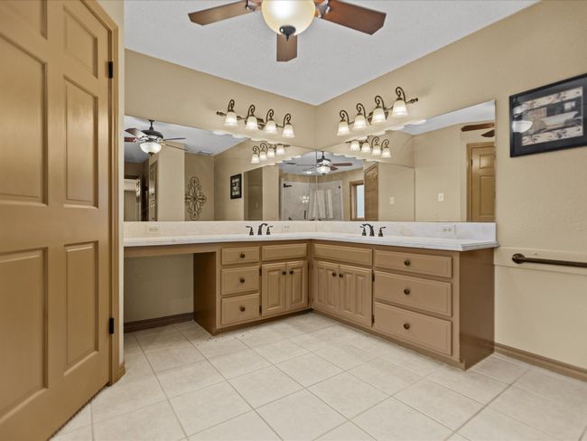 Master bathroom with a ceiling fan, double vanity, tile patterned floors, and baseboards | Image 25