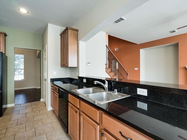 Kitchen featuring black appliances, a sink, baseboards, light tile patterned floors, and dark countertops | Image 20