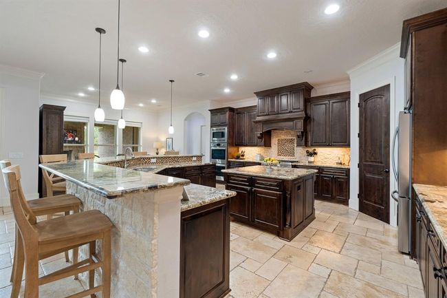 Cooking will never feel like a chore in this large and exquisite Kitchen! This Kitchen meticulously marries elegance, with form and function. The warm walnut-colored cabinets are counterbalanced with the rough-edged, cream-colored, brick backsplash. | Image 15