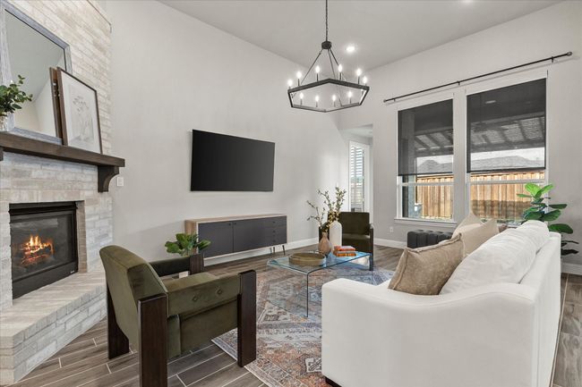 Living room with wood finished floors, a chandelier, a brick fireplace, and recessed lighting | Image 12