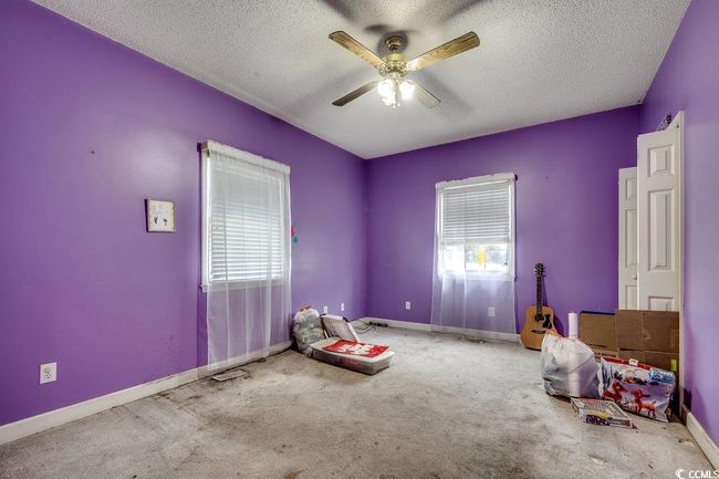 Unfurnished bedroom with multiple windows, a textured ceiling, carpet floors, baseboards, and ceiling fan | Image 19