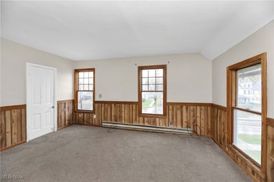 Carpeted spare room with wood walls, plenty of natural light, and a baseboard heating unit | Image 2