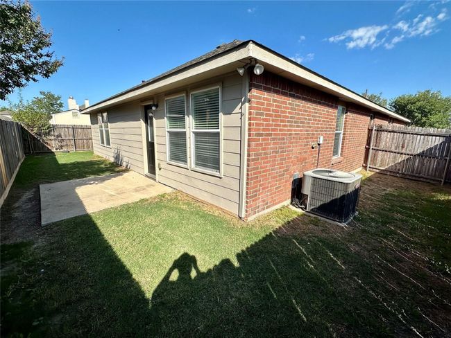 Rear view of house with a patio area, brick siding, a fenced backyard, a lawn, and central AC | Image 15