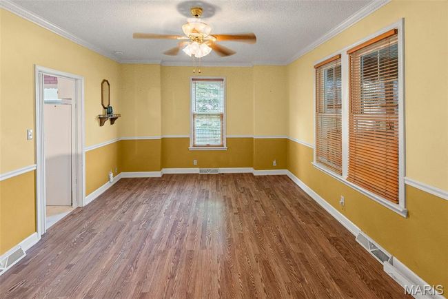 Spare room with wood finished floors, a ceiling fan, a textured ceiling, and ornamental molding | Image 13