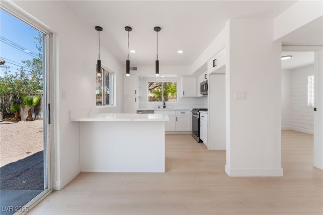 Kitchen with appliances with stainless steel finishes, white cabinets, light wood-style floors, light countertops, and recessed lighting | Image 7