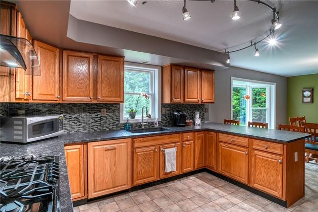 Kitchen with black range with gas stovetop, sink, backsplash, and plenty of natural light | Image 19
