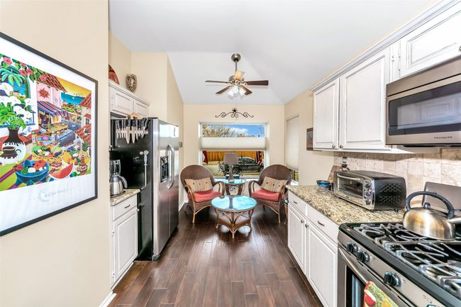 Kitchen with appliances with stainless steel finishes, lofted ceiling, backsplash, white cabinets, and dark wood finished floors | Image 4
