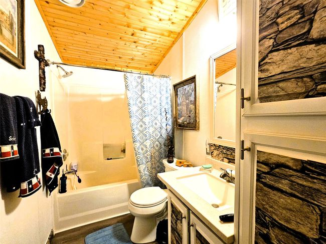 Full bathroom featuring wooden ceiling, toilet, wood finished floors, vanity, and shower / tub combo | Image 15