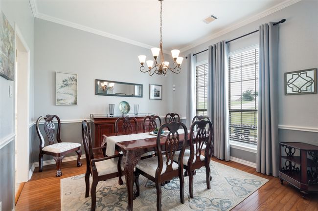 Dining room with ornamental molding, a chandelier, and wood finished floors | Image 11