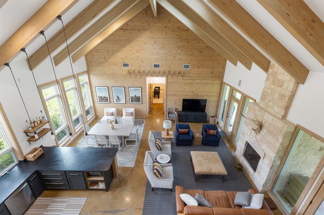 Living area with high vaulted ceiling, beamed ceiling, wood walls, and a stone fireplace | Image 22