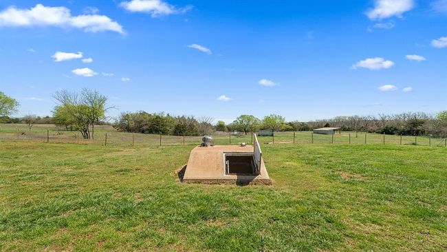 Entry to storm shelter featuring a rural view, a yard, and fence | Image 17